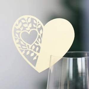 Detail der lasergeschnittenen Herz-Platzkarte aus cremefarbenem Perlmuttpapier am Glas