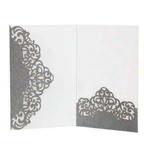 Close-up of laser-cut silver glitter wedding invitation with intricate vine hollow pattern