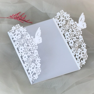 Close-up of laser-cut butterfly invitation card with elegant white floral patterns