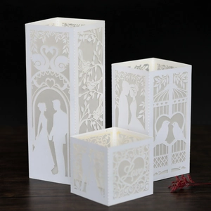 Three white laser-cut paper lanterns with romantic silhouettes for wedding decoration