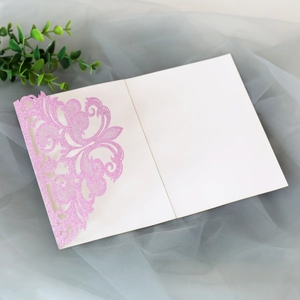 Macro detail of laser-cut pink glitter wedding invitation with delicate lace pattern