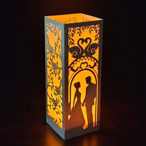 White laser-cut paper candle lantern featuring romantic heart and silhouette patterns