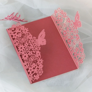 Detail of laser-cut burgundy invitation card featuring intricate butterfly and floral patterns