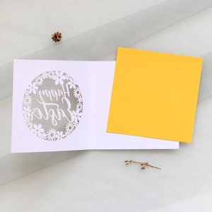 Détail d'une carte de Pâques découpée au laser avec motif fleuri et insert jaune