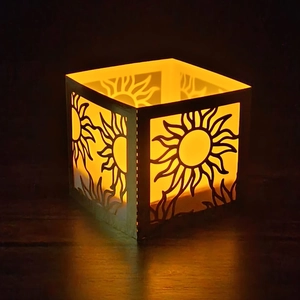 Close-up of laser-cut sunburst pattern on square bronze lantern with warm LED glow