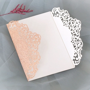 Détail macro d'une invitation de mariage découpée au laser avec paillettes or rose et dentelle