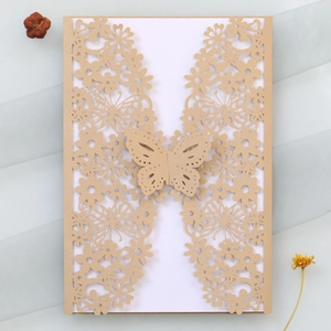Macro detail of champagne gold laser-cut invitation card with butterfly clasp design