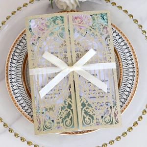 Detail of glitter laser cut wedding invitation with champagne gold finish and silk ribbon
