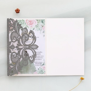 Detail of silver glitter laser-cut wedding invitation with floral inner card and floral accents