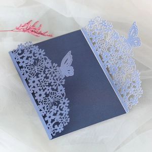 Macro shot of navy blue laser-cut invitation sleeve with floral and butterfly patterns