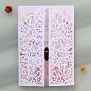 Detail of laser-cut wedding invitation with pink floral insert and elegant bow hollow design
