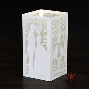 Detail of white laser-cut paper lantern featuring romantic couple and floral patterns