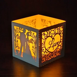 Detailed view of white hollow candle lantern with romantic couple silhouette and Love text