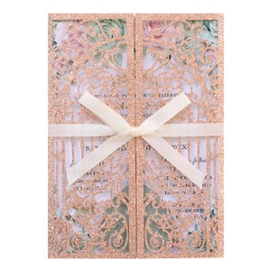 Detail of rose gold laser cut wedding invitation with glitter finish and silk ribbon bow
