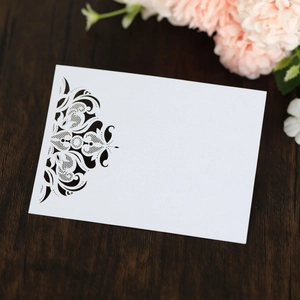 Macro detail of laser-cut lace pattern on pearl white wedding place card over wooden table