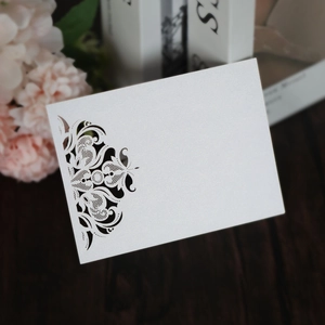 Close-up of laser-cut pearl white invitation card with elegant floral hollow design