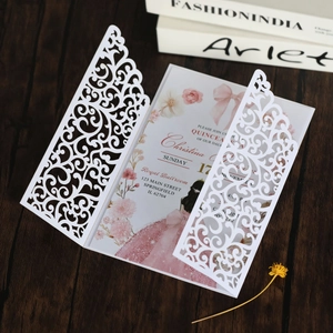 Macro shot of laser-cut wedding invitation featuring elegant patterns and pink floral inner card