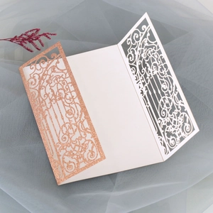 Macro view of laser-cut wedding invitation featuring rose gold glitter and vine patterns