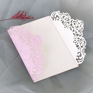 Détail des motifs floraux découpés au laser rose pailleté sur une invitation de mariage