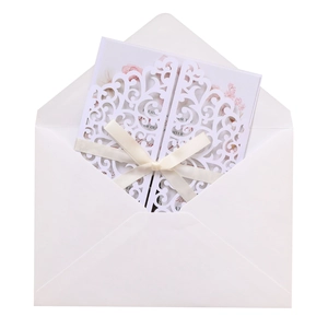 Detail of laser-cut wedding invitation with elegant white ribbon and floral inner card