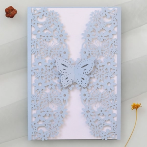 Detail of light blue laser-cut wedding invitation with butterfly buckle and floral patterns