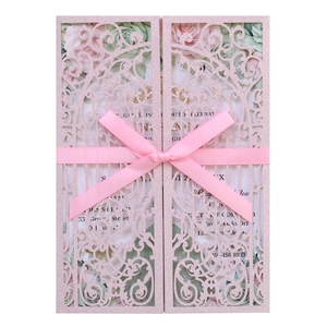 Close-up of pink glitter laser-cut wedding invitation with elegant ribbon bow detailing
