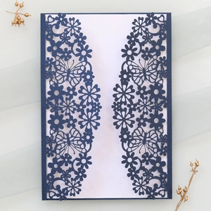 Macro view of navy blue laser-cut invitation featuring intricate butterflies and daisies