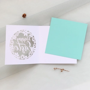 Détail d'une carte de Pâques découpée au laser avec motifs marguerites et doublure menthe
