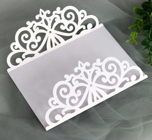 Detailed laser-cut hollow patterns on white wedding invitation envelopes in macro view