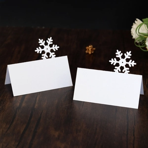 Detailed laser-cut snowflake place cards for Christmas tables on dark wood background