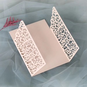 Macro shot of laser-cut floral patterns on a pink wedding invitation card with mesh fabric