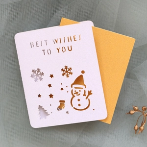 Close-up of laser-cut Christmas card with snowman motifs and a gold envelope
