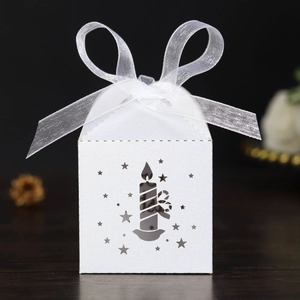 Macro detail of laser-cut white favor box with star patterns and organza ribbon