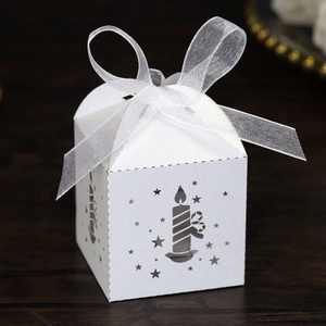 Close-up of white laser-cut Christmas gift box with candle pattern and organza bow