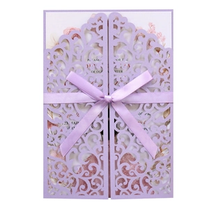 Detail of laser-cut floral lavender wedding invitation with purple ribbon bow and card
