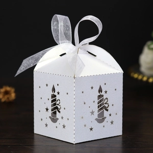 Detail of white laser-cut Christmas candy box with hollow candle and star patterns