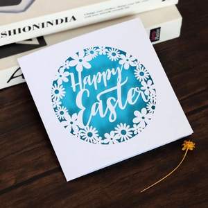 Détail d'une carte de Pâques découpée au laser avec motif floral bleu sur papier blanc