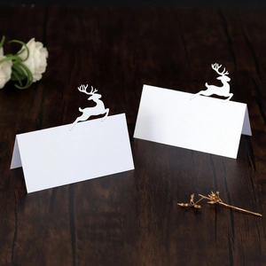 Detail of white laser-cut reindeer place cards on a rustic wooden table for Christmas