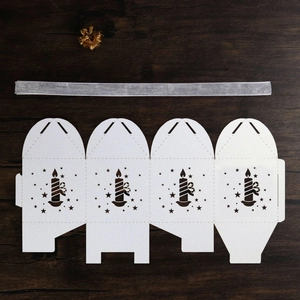 Flat lay of white laser-cut Christmas gift box with star patterns and silver ribbon