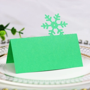 Detail of green fold-over place card with snowflake laser cut on white porcelain plate