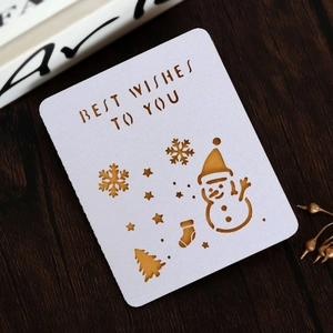 Detail of white laser-cut Christmas card with Best Wishes text on a dark wood background