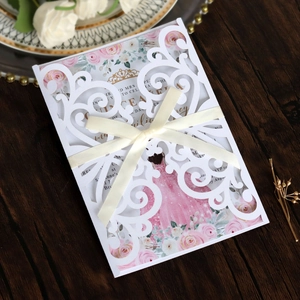 Detail of pink floral laser cut wedding invitation with elegant ribbon and white envelope