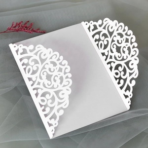 Detail view of laser-cut lace floral pattern on white wedding invitation cards