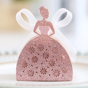 Détail de la boîte à dragées rose pailletée avec motif robe ajourée et ruban