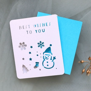 Detail of laser-cut Christmas card with snowman, snowflakes and blue insert card