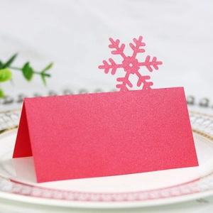 Detail of red pearl paper snowflake table card on white plate for Christmas dinner