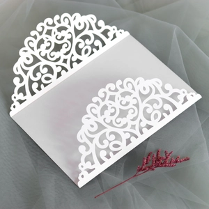 Detailed laser-cut scrollwork on white wedding invitation covers with red floral decor