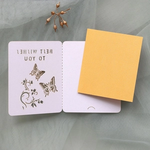 Macro detail of a laser-cut white butterfly card with a yellow insert and Best Wishes text