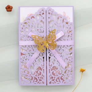 Detail of light purple laser-cut invitation featuring silk bow and gold butterfly accent