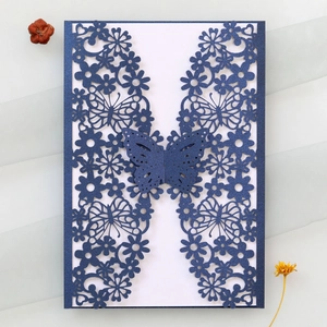 Detail of laser-cut navy blue wedding invitation with intricate butterfly and floral patterns